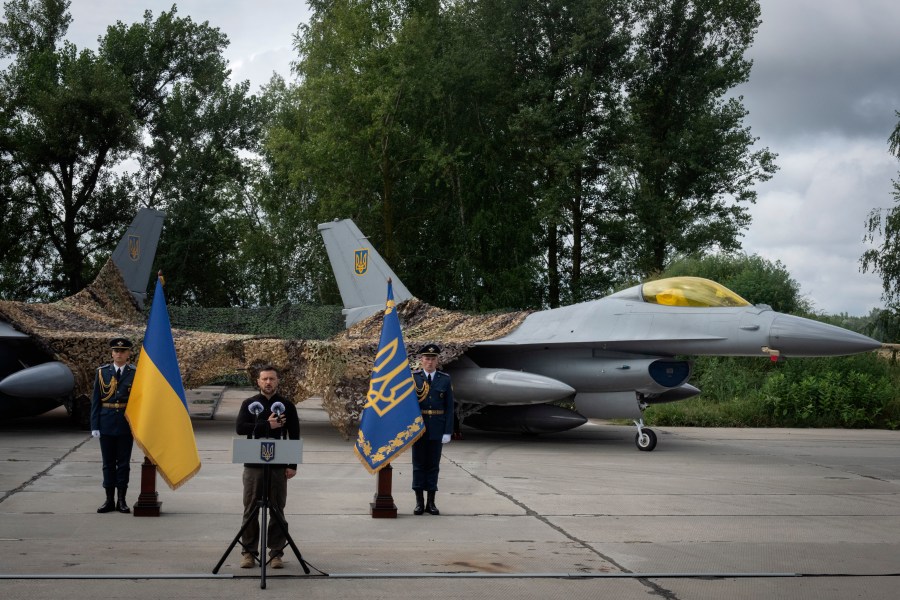 Ukraine's President Volodymyr Zelenskyy talks on the occasion of the Air Forces Day standing against the background of Ukraine's Air Force's F-16 fighter jets in an undisclosed location in Ukraine, Sunday, Aug. 4, 2024. The F-16 fighter jets that have been delivered to Ukraine by Western countries will be flying sorties in Ukrainian skies and helping the country's current fleet of Soviet-era jets to counter Russia's invasion. (AP Photo/Efrem Lukatsky)