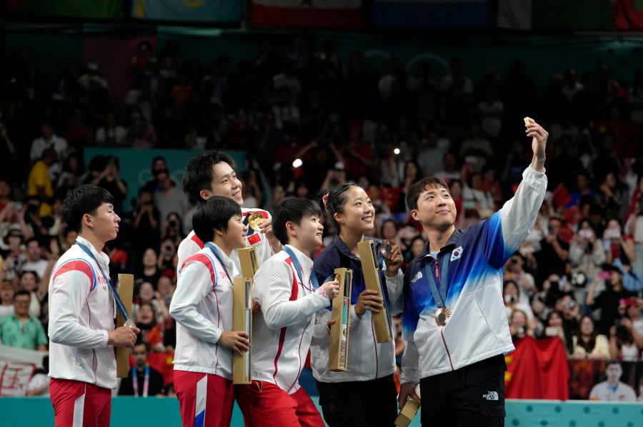 FILE - South Korea's Lim Jonghoon, right, takes a selfie with North Korea's Ri Jong Sik, left, and Kim Kum, second left, China's Wang Chuqin, background, and Sun Yingsha, center, and his teammate Shin Yubin, right, and Lim Jonghoon during the medal ceremony at the 2024 Summer Olympics, July 30, 2024, in Paris, France. (AP Photo/Petros Giannakouris, File)