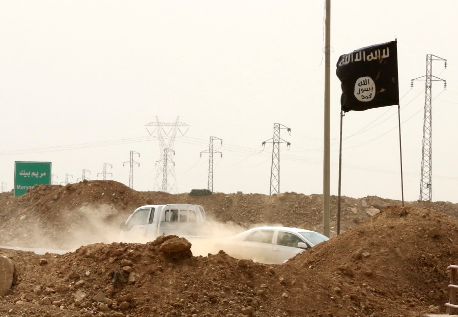 FILE - Islamic State militants pass a checkpoint bearing the group's trademark black flag in the village of Maryam Begg in Kirkuk, 180 miles north of Baghdad, Iraq, Sept. 29, 2014. (AP Photo/Hadi Mizban, File)