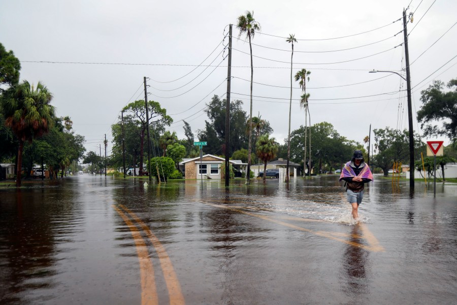 Carter Grooms, 25, of Tampa, wades through the streets in the Shore Acres neighborhood of St. Petersburg, Fla., Monday morning, Aug 5, 2024, as Hurricane Debby passed the Tampa Bay area offshore. (Dylan Townsend/Tampa Bay Times via AP)