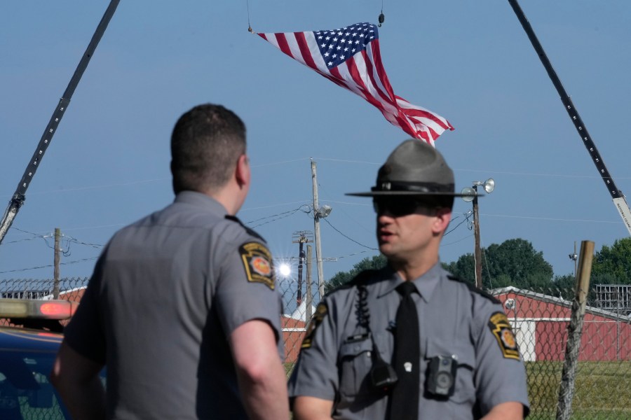 FILE - Police officers stand at a road leading to the site of the Trump rally, where access is closed, as investigations into the assassination attempt on former President Donald Trump continue, in Butler, Pa., July 14, 2024. (AP Photo/Sue Ogrocki, File)