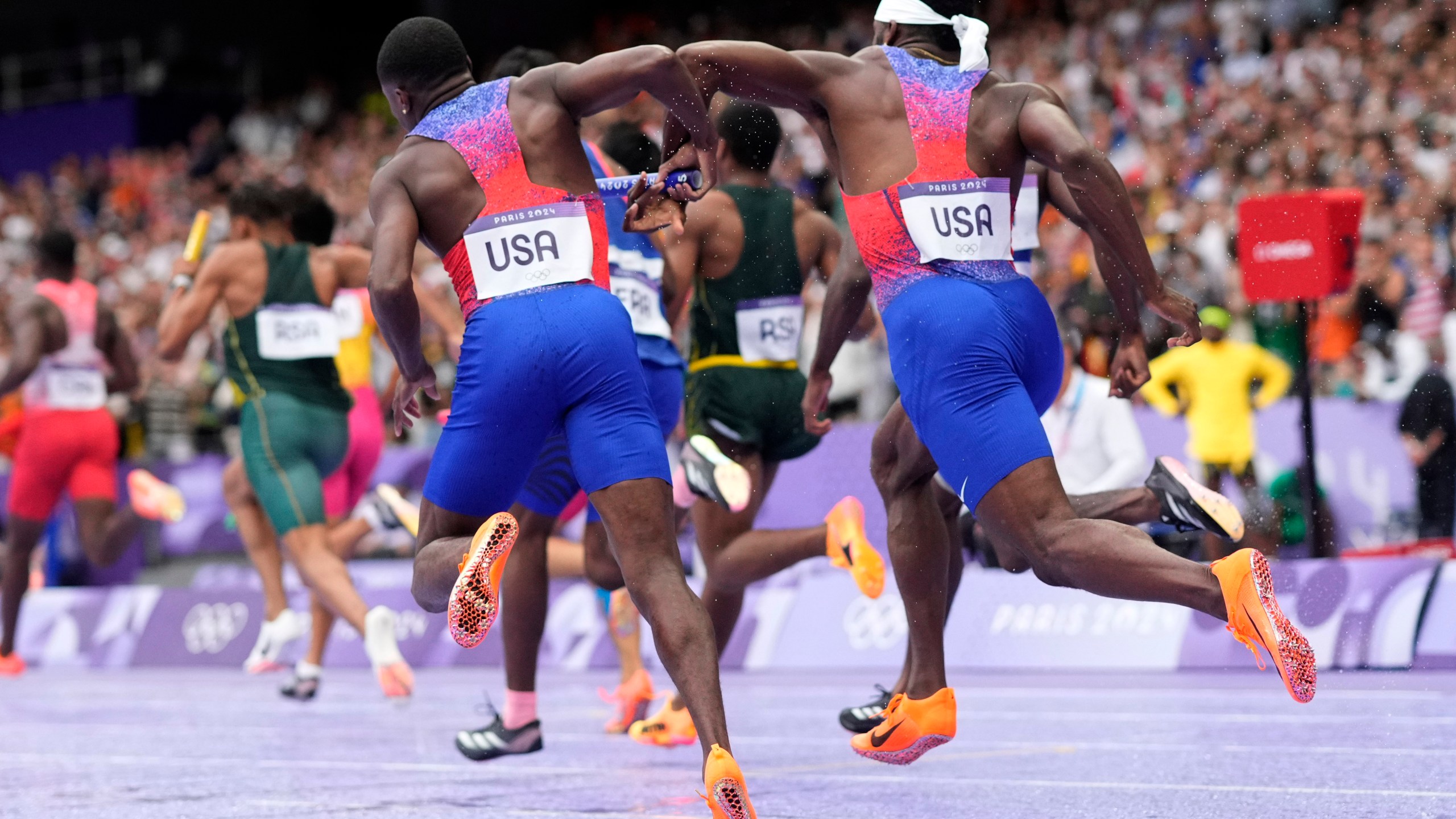 Christian Coleman, left, of the United States, struggles to hand the baton to teammate Kenneth Bednarek, in the men's 4x100-meter relay final at the 2024 Summer Olympics, Friday, Aug. 9, 2024, in Saint-Denis, France. (AP Photo/Bernat Armangue)