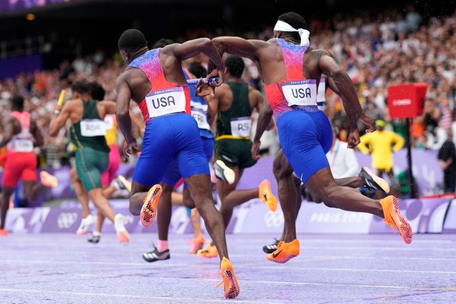 Christian Coleman, left, of the United States, struggles to hand the baton to teammate Kenneth Bednarek, in the men's 4x100-meter relay final at the 2024 Summer Olympics, Friday, Aug. 9, 2024, in Saint-Denis, France. (AP Photo/Bernat Armangue)