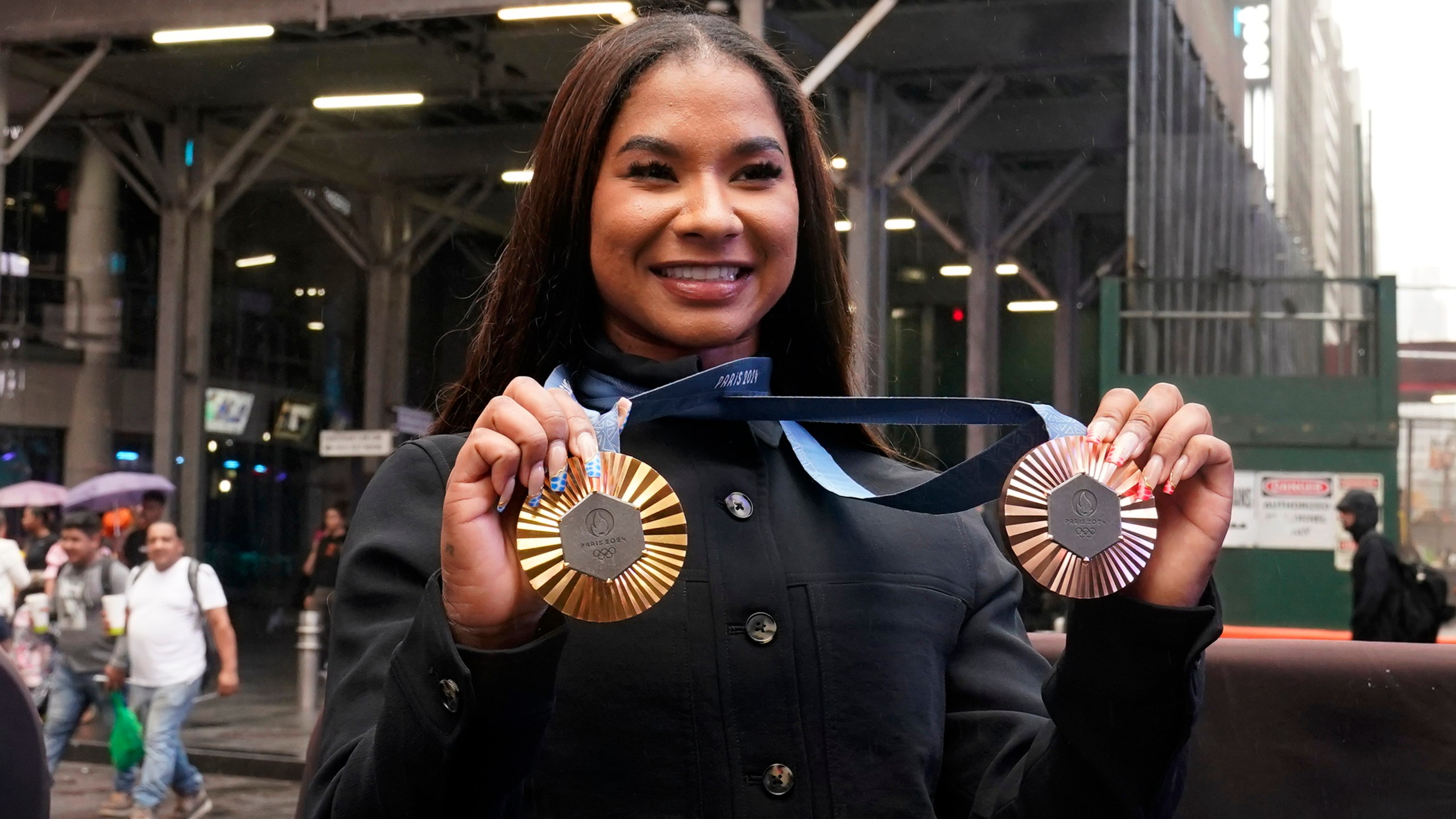 Two-time U.S. Olympic gymnast medalist Jordan Chiles shows her medals after ringing the closing bell at the Nasdaq MarketSite, in New York's Times Square, Thursday, Aug. 8, 2024. (AP Photo/Richard Drew)