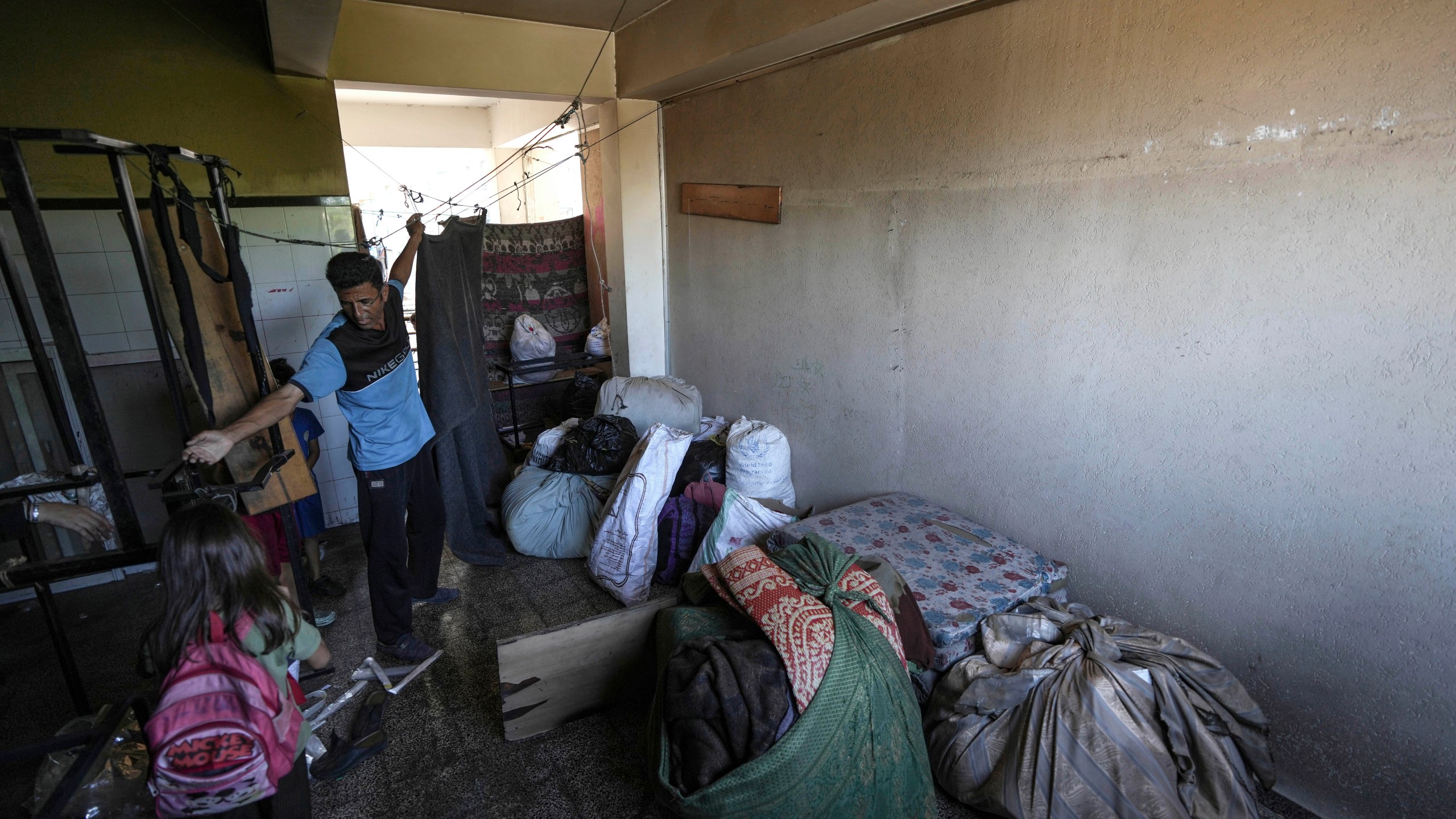 A Palestinian packs up to evacuate a school that had been his shelter, in eastern Deir al-Balah, Gaza Strip, Friday, Aug. 16, 2024, after the Israeli military dropped leaflets asking civilians to evacuate from the area, saying forces plan to respond to rocket fire that targeted Israel. (AP Photo/Abdel Kareem Hana)