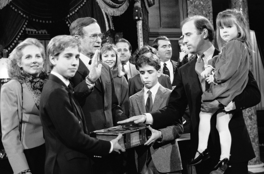 FILE - Sen. Joe Biden, D-Del., holds his daughter Ashley while taking a mock oath of office from Vice President George Bush during a ceremony, Jan. 3, 1985, on Capitol Hill, in Washington. Biden's sons Beau and Hunt hold the bible during the ceremony. (AP Photo/Lana Harris, File)