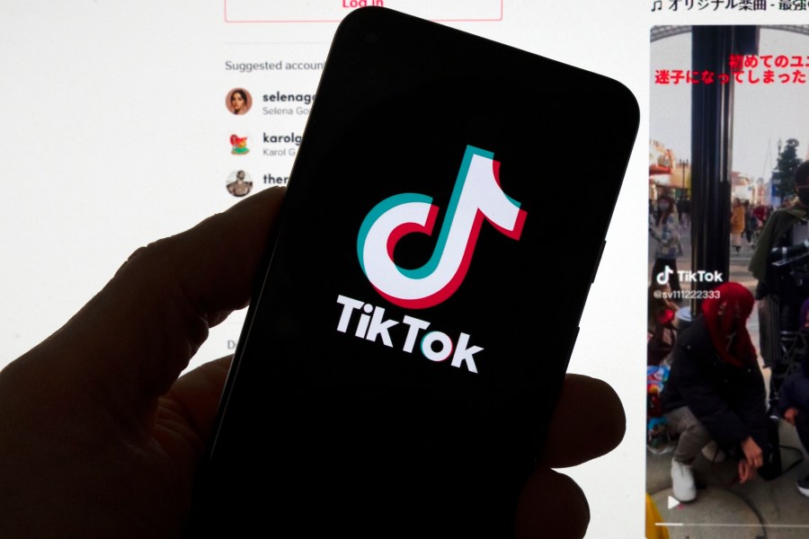 FILE - The TikTok logo is seen on a mobile phone in front of a computer screen which displays the TikTok home screen, March 18, 2023, in Boston. (AP Photo/Michael Dwyer, File)