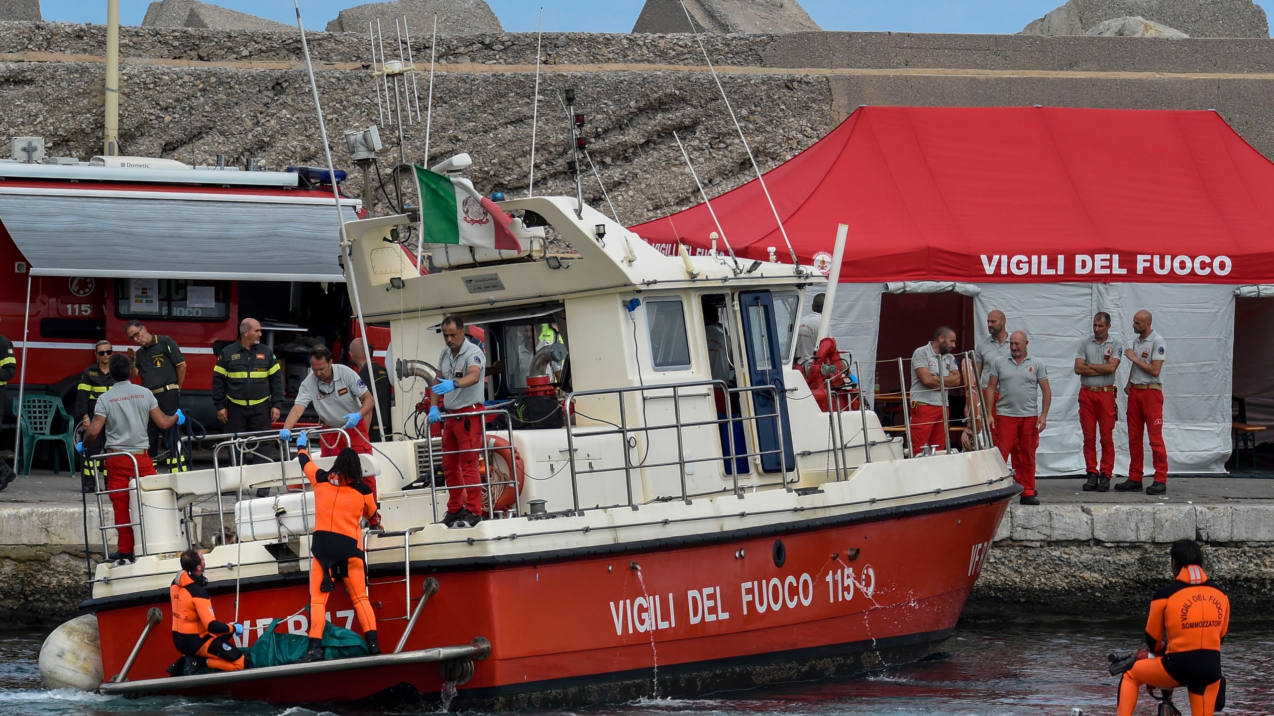 Italian firefighter divers bring ashore in a green bag the body of one of the victims of the UK flag vessel Bayesian, Wednesday, Aug. 21, 2024. The luxury sail yacht was hit by a violent sudden storm and sunk early Monday, while at anchor off the Sicilian village of Porticello near Palermo, in southern Italy. (AP Photo/Salvatore Cavalli)