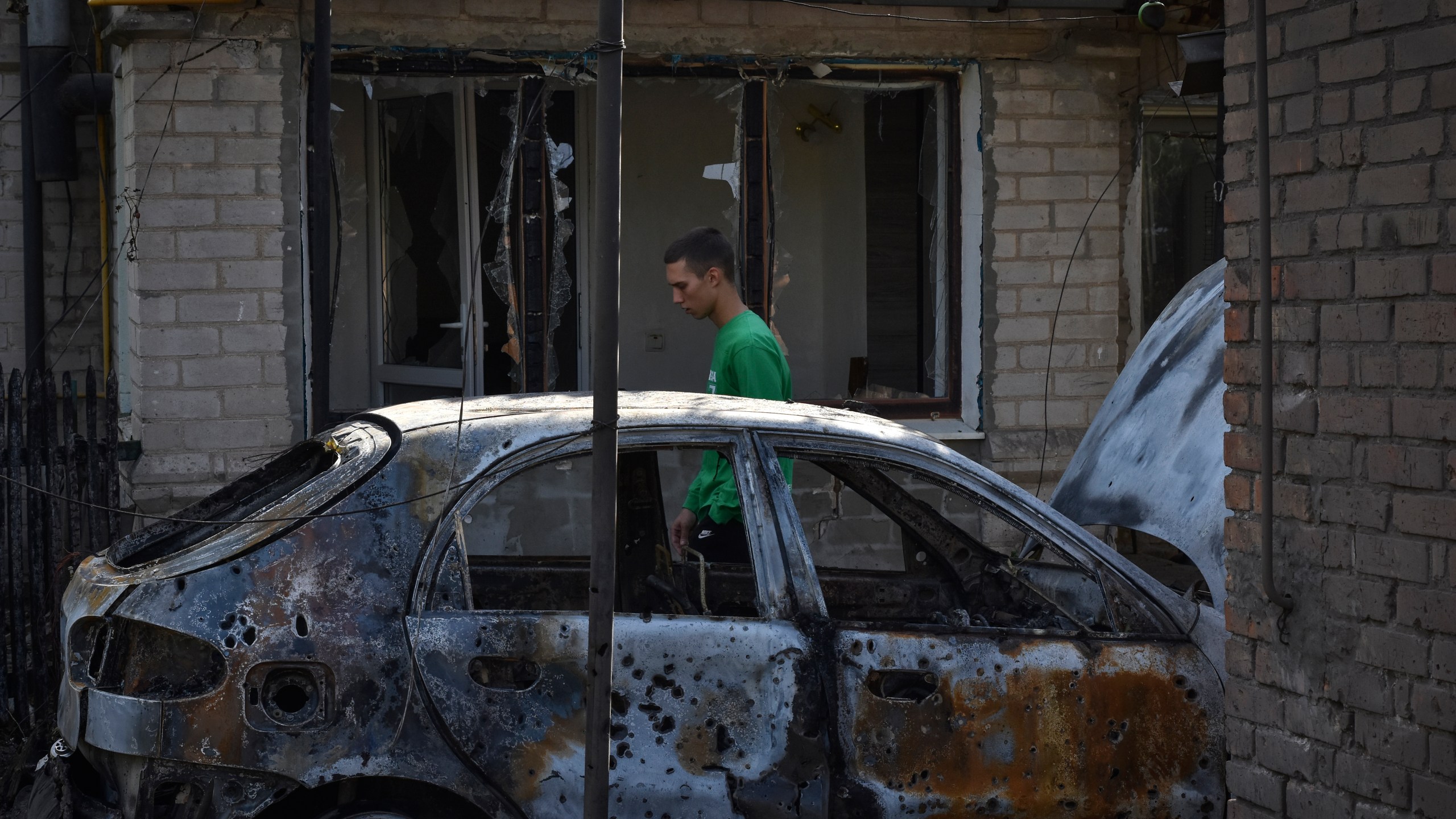 A man passes by a damaged car after a Russian rocket attack in Malokaterynivka, Zaporizhzhia region, Ukraine, Wednesday, Aug. 21, 2024. (AP Photo/Andriy Andriyenko)