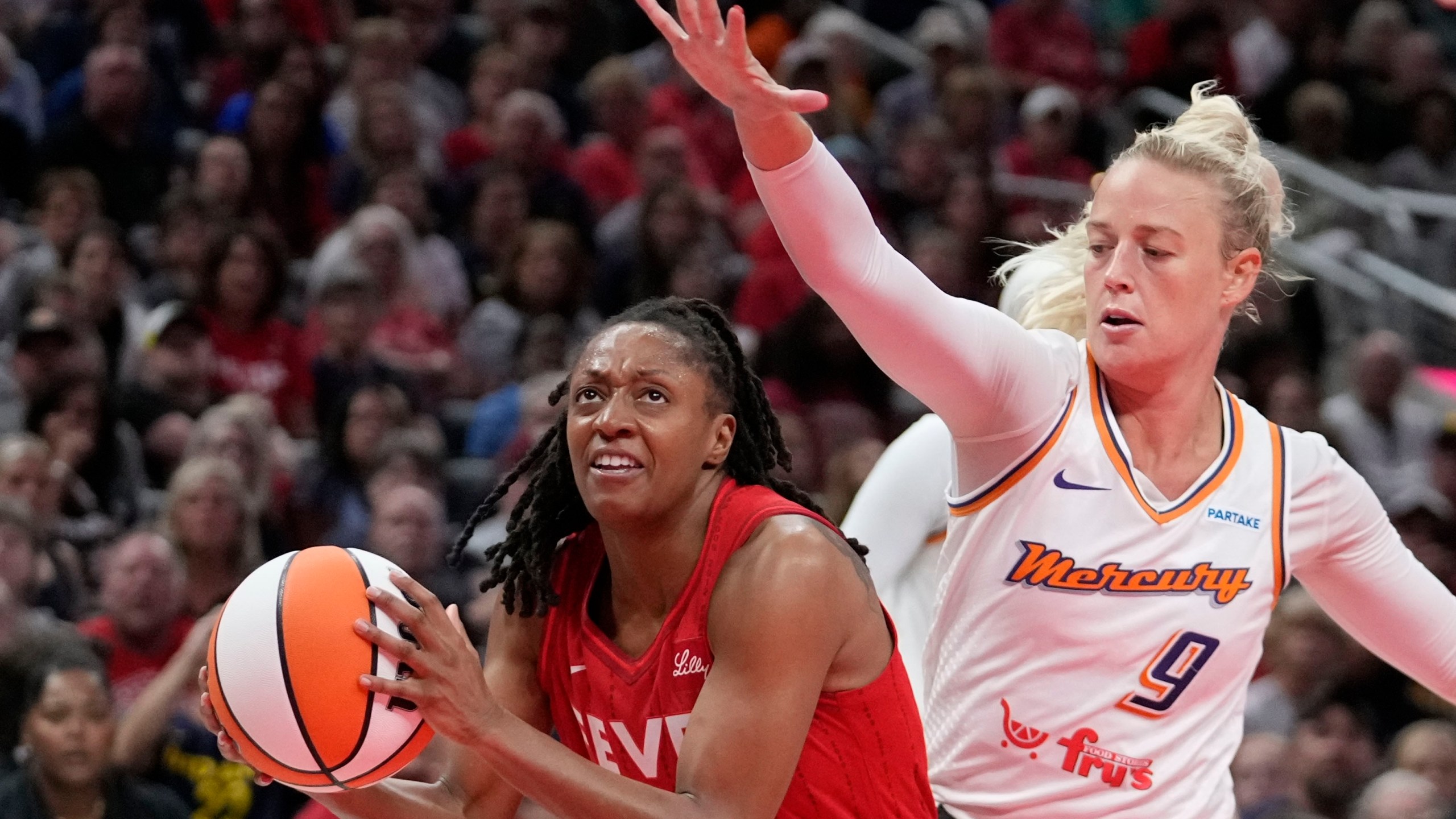 Indiana Fever's Kelsey Mitchell, left, goes to the basket against Phoenix Mercury's Sophie Cunningham (9) during the second half of a WNBA basketball game, Friday, Aug. 16, 2024, in Indianapolis. (AP Photo/Darron Cummings)