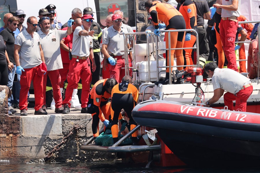 Italian firefighter divers bring ashore in a plastic bag the body of one of the victims of a shipwreck, in Porticello, Sicily, southern Italy, Friday Aug. 23, 2024. Italian rescuers brought ashore the body of the final missing person who was on a superyacht that sunk off the coast of Sicily. (Alberto Lo Bianco/LaPresse via AP)