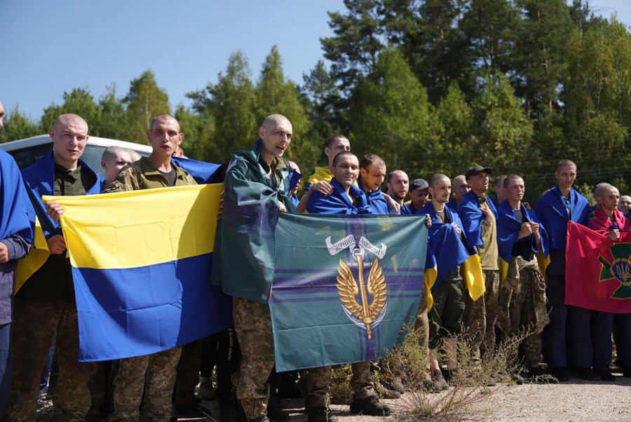 In this photo provided by the Ukrainian Presidential Press Office on Saturday, Aug. 24, 2024, Ukrainian prisoners of war hold their units flags after a prisoners exchange at an undisclosed location in Ukraine. (Ukrainian Presidential Press Office via AP)