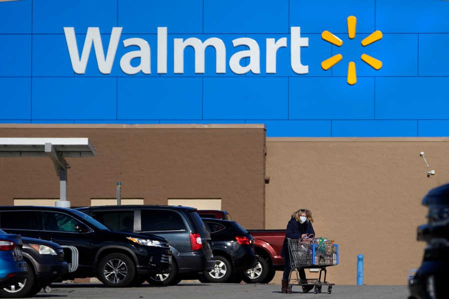 FILE - A woman wheels a cart with her purchases out of a Walmart store, Nov. 18, 2020, in Derry, N.H. (AP Photo/Charles Krupa, File)