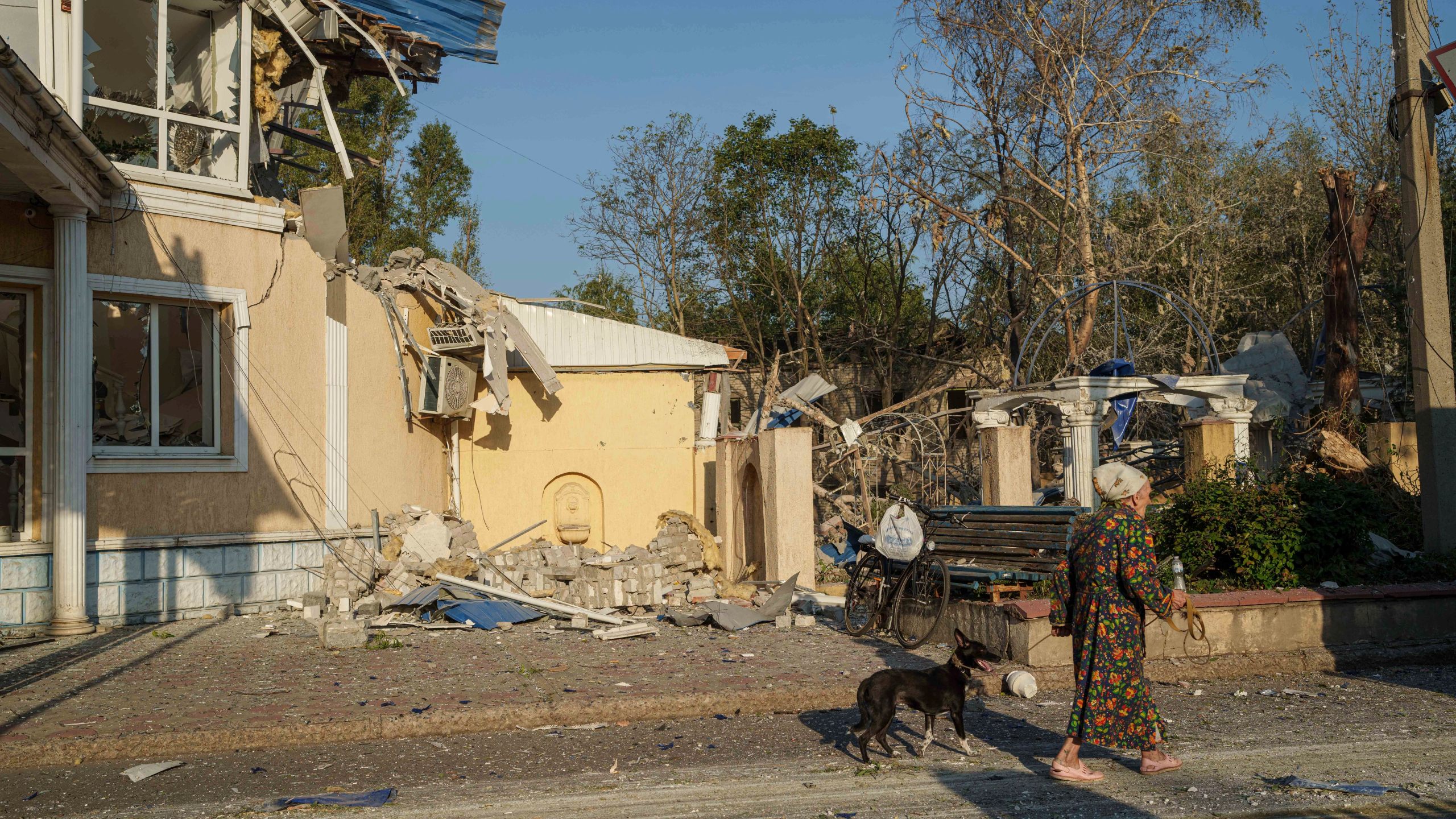 A woman walks with her dog in front of the Sapphire hotel which was destroyed by a Russian rocket attack in Kramatorsk, Donetsk region, Ukraine, Sunday, Aug. 25, 2024. (AP Photo/Evgeniy Maloletka)