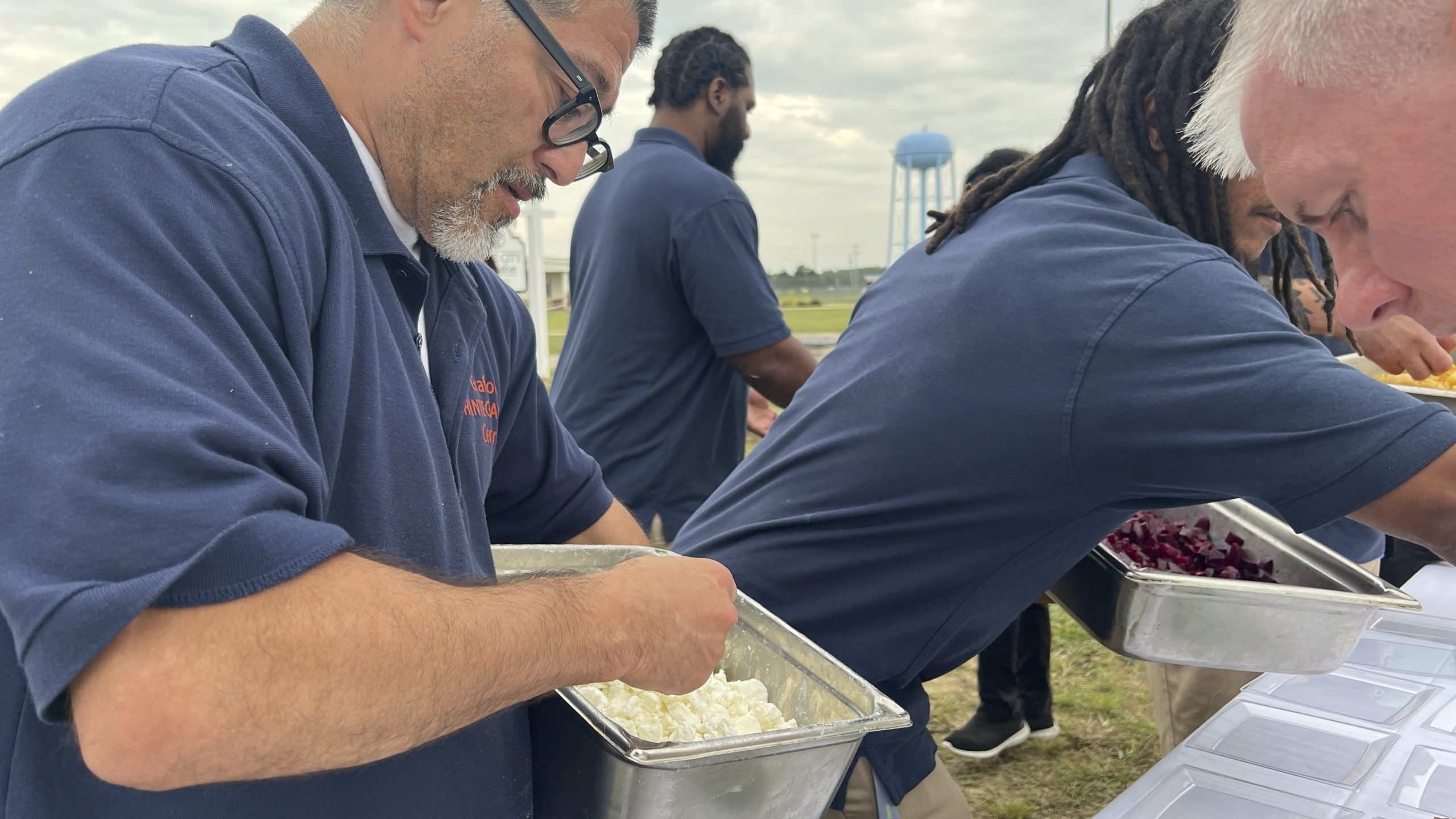 Joshua Freshwater, 53, puts feta cheese on salads during a five-course dinner event at the Grafton Reintegration Center on Thursday, Aug. 15, 2024 in Grafton, Ohio. (AP Photo/Patrick Aftoora Orsagos)