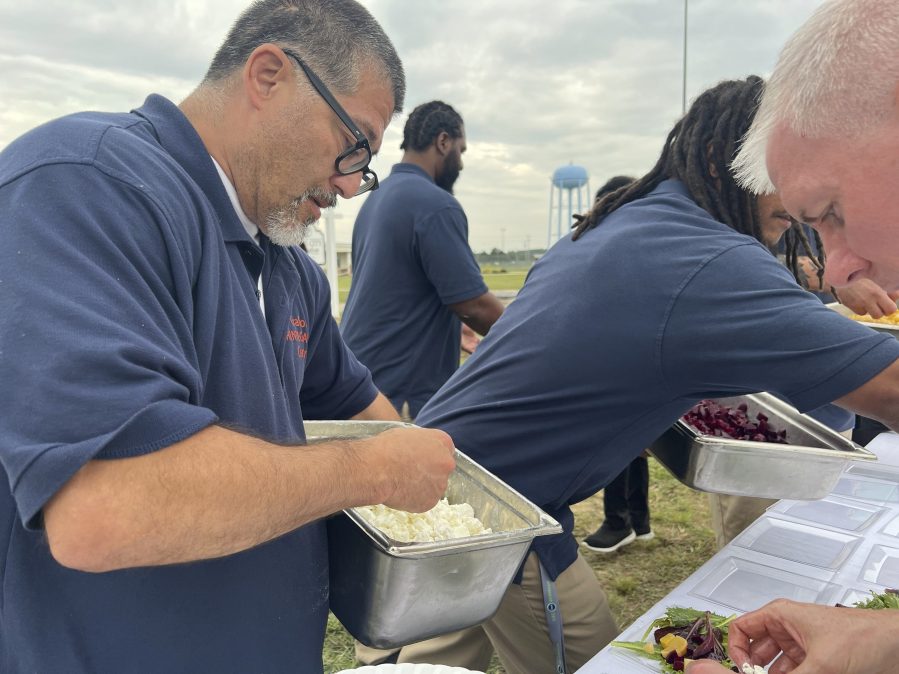 Joshua Freshwater, 53, puts feta cheese on salads during a five-course dinner event at the Grafton Reintegration Center on Thursday, Aug. 15, 2024 in Grafton, Ohio. (AP Photo/Patrick Aftoora Orsagos)