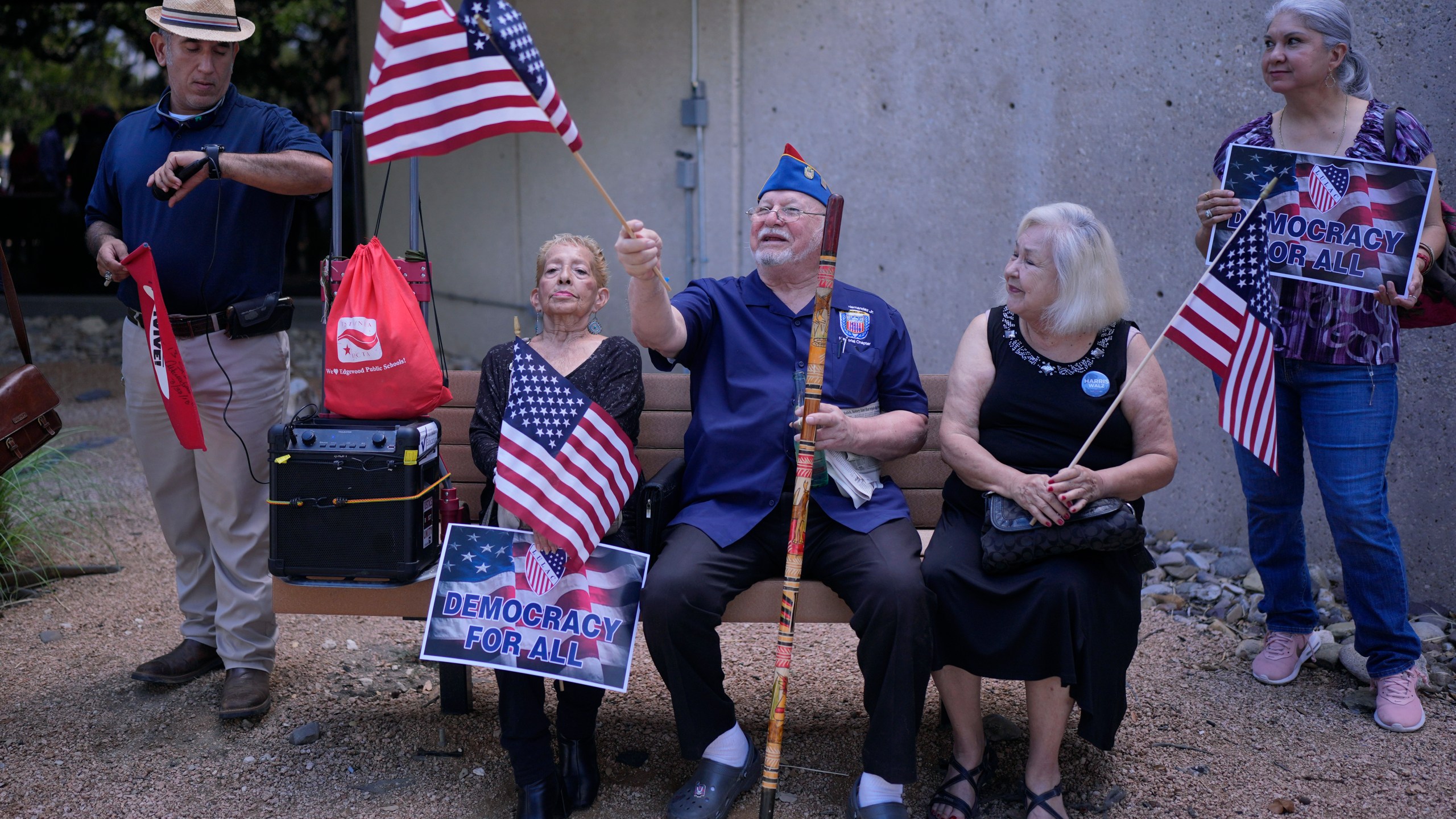 Roman Rena, center, waves a flag at a news conference where Officials with the League of United Latin American Citizens, or LULAC, held a news conference to respond to allegations by Texas Attorney General Ken Paxton, Monday, Aug. 26, 2024, in San Antonio. (AP Photo/Eric Gay)