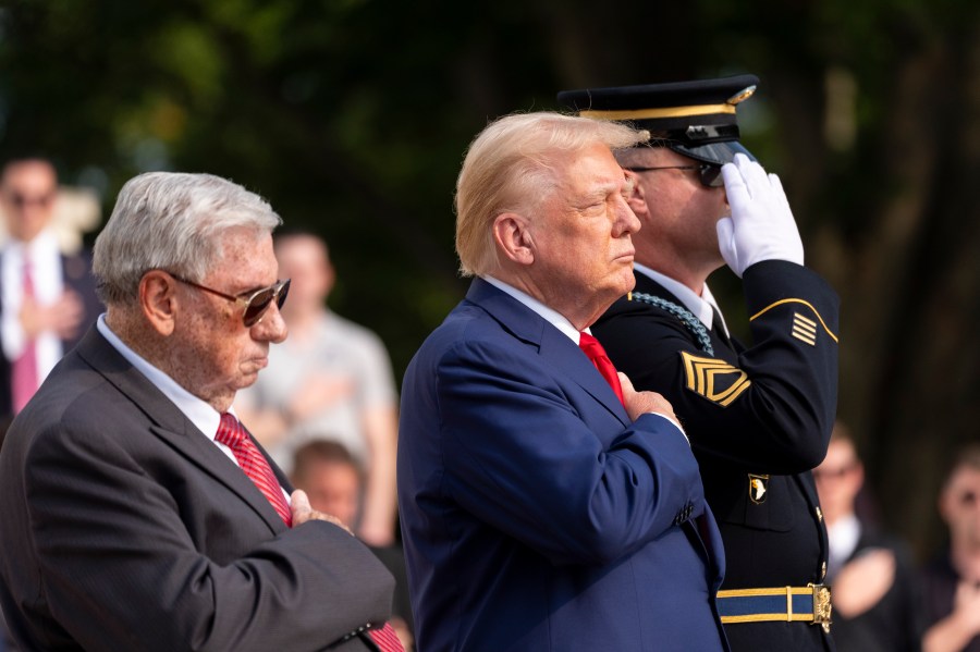 Bill Barnett, left, grandfather of Darin Taylor Hoover, and Republican presidential nominee former President Donald Trump place their hands over their heart after placing a wreath at the Tomb of the Unknown Solider in honor of Staff Sgt. Darin Taylor Hoover at Arlington National Cemetery, Monday, Aug. 26, 2024, in Arlington, Va. (AP Photo/Alex Brandon)