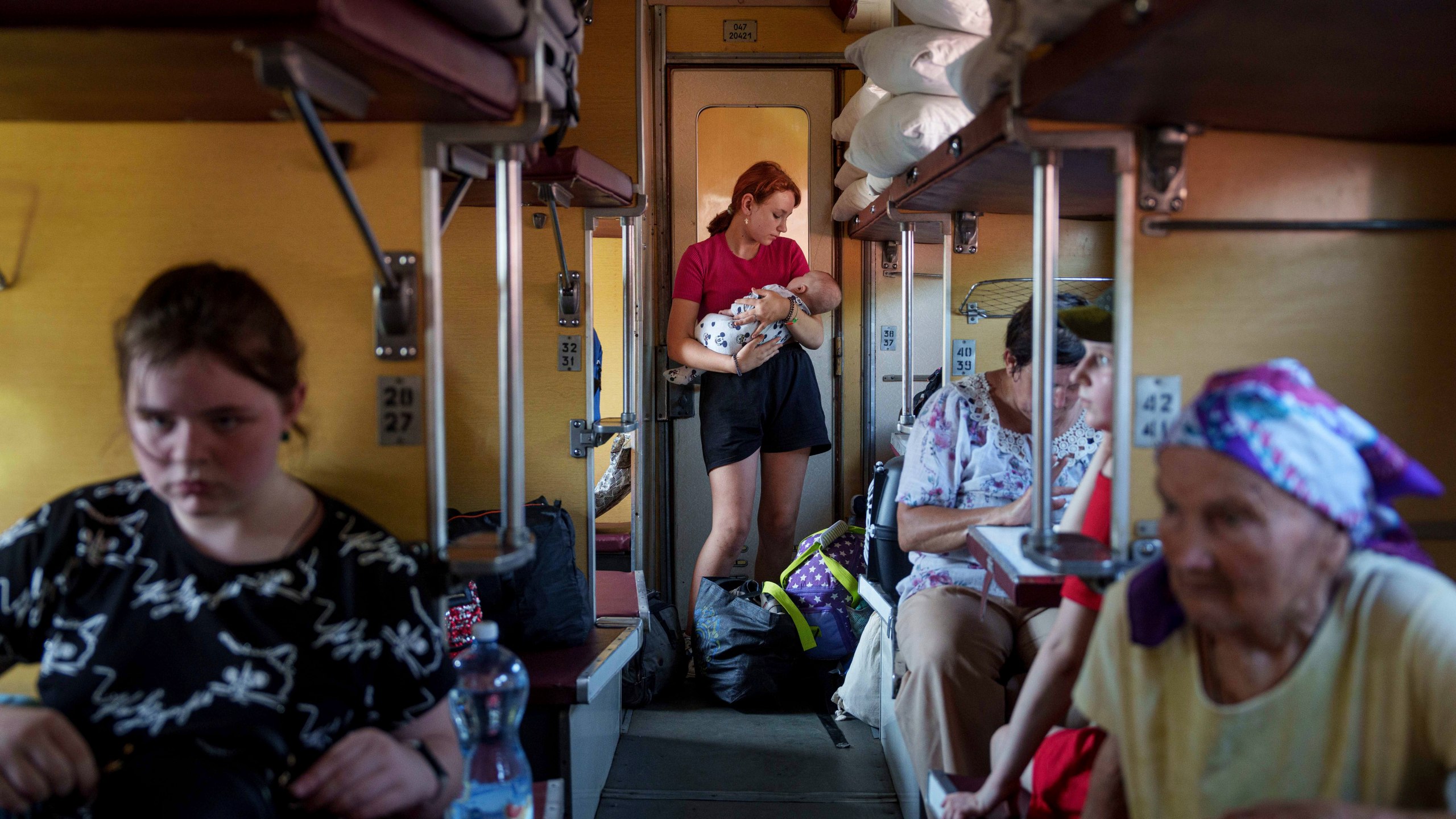 A girl calms her sister on an evacuation train in Pokrovsk, Donetsk region, Ukraine, Friday, Aug. 23, 2024. (AP Photo/Evgeniy Maloletka)