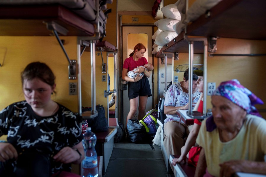 A girl calms her sister on an evacuation train in Pokrovsk, Donetsk region, Ukraine, Friday, Aug. 23, 2024. (AP Photo/Evgeniy Maloletka)