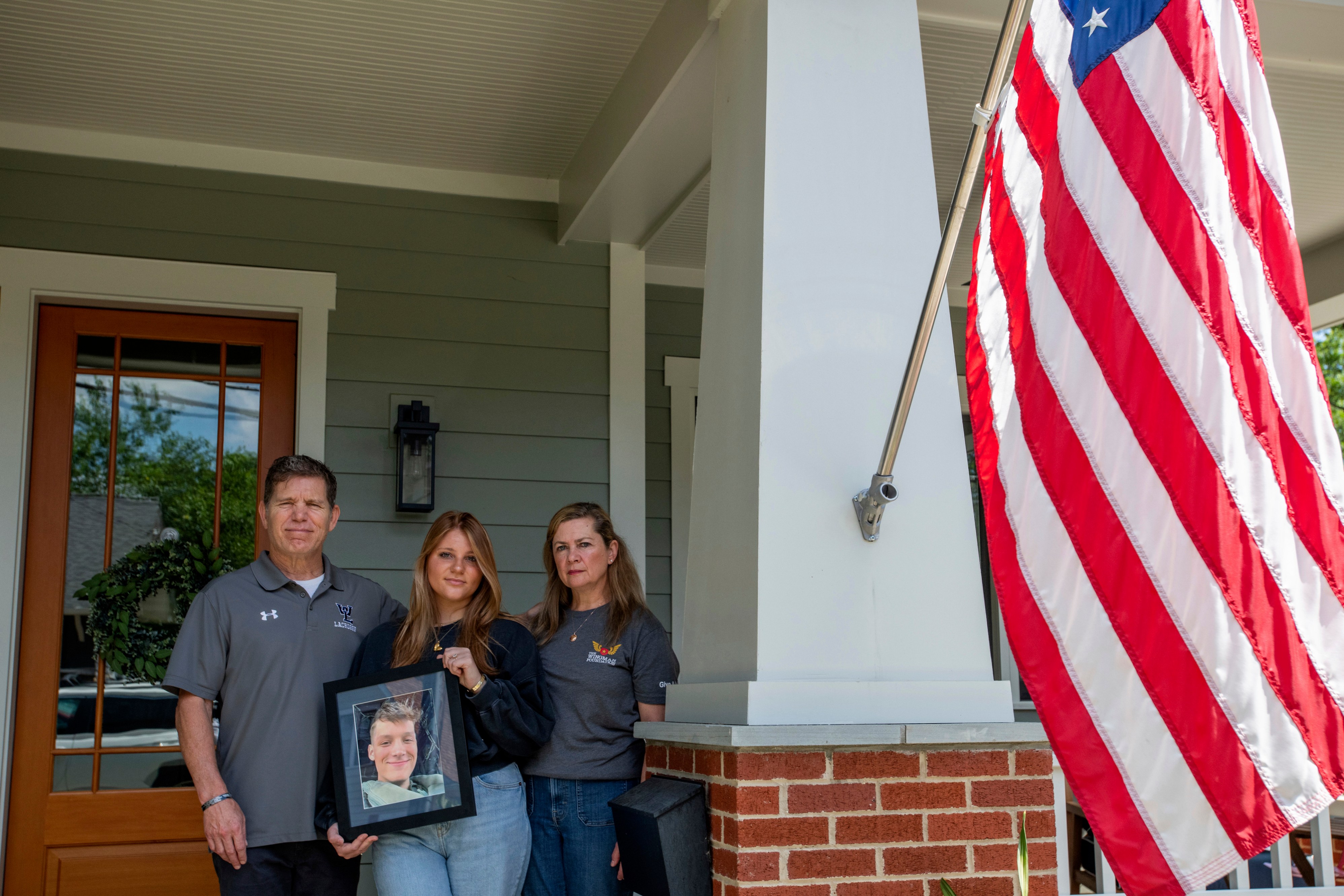 Family members of Marine Corporal Spencer R. Collart, from left, father Bart Collart, sister Gwyneth Collart and mother Alexia Collart, hold his portrait as they pose for a photo at their home in Arlington, Va., Thursday, June 19, 2024.