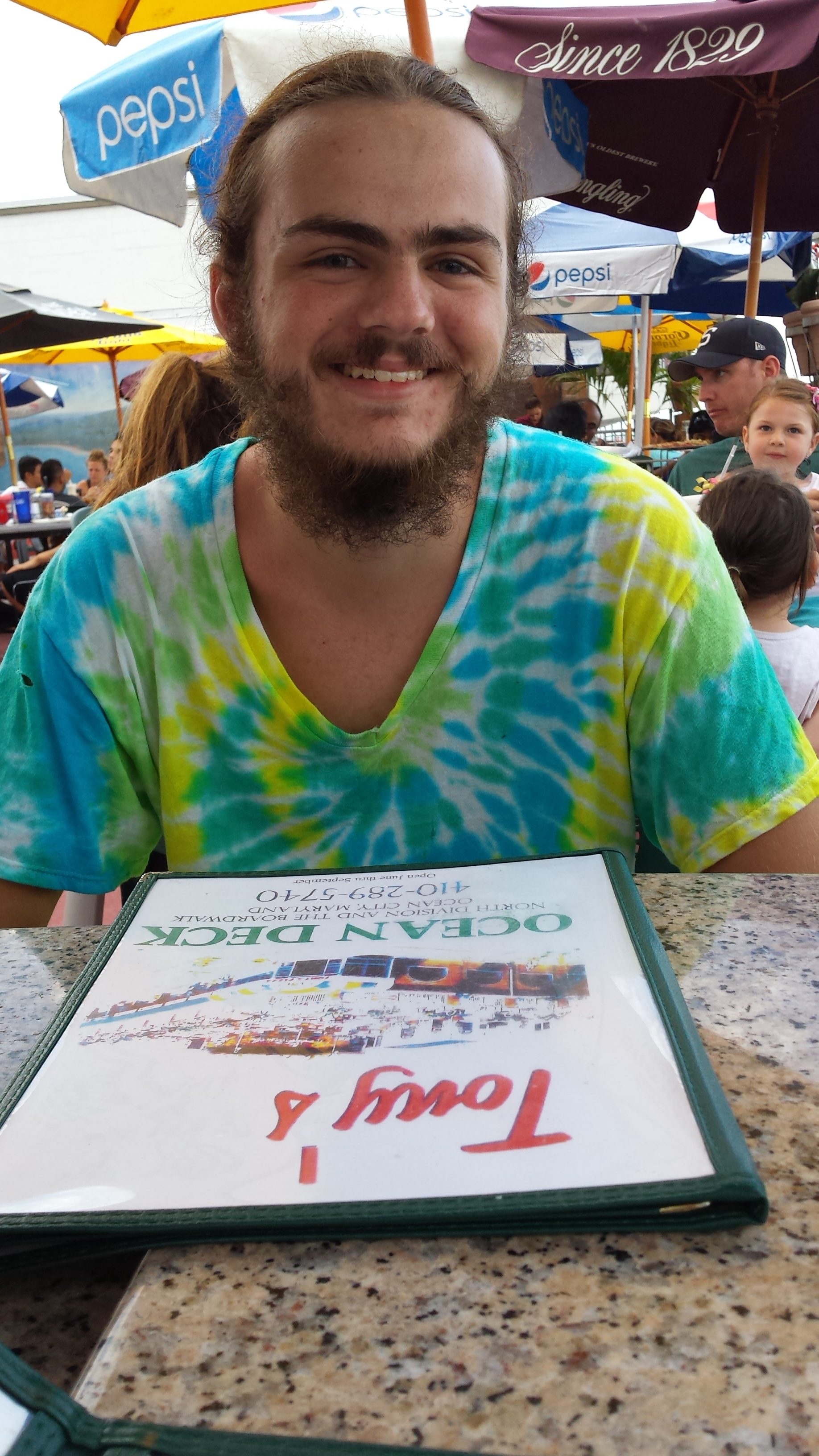 A young bearded man in a tie-dye shirt.