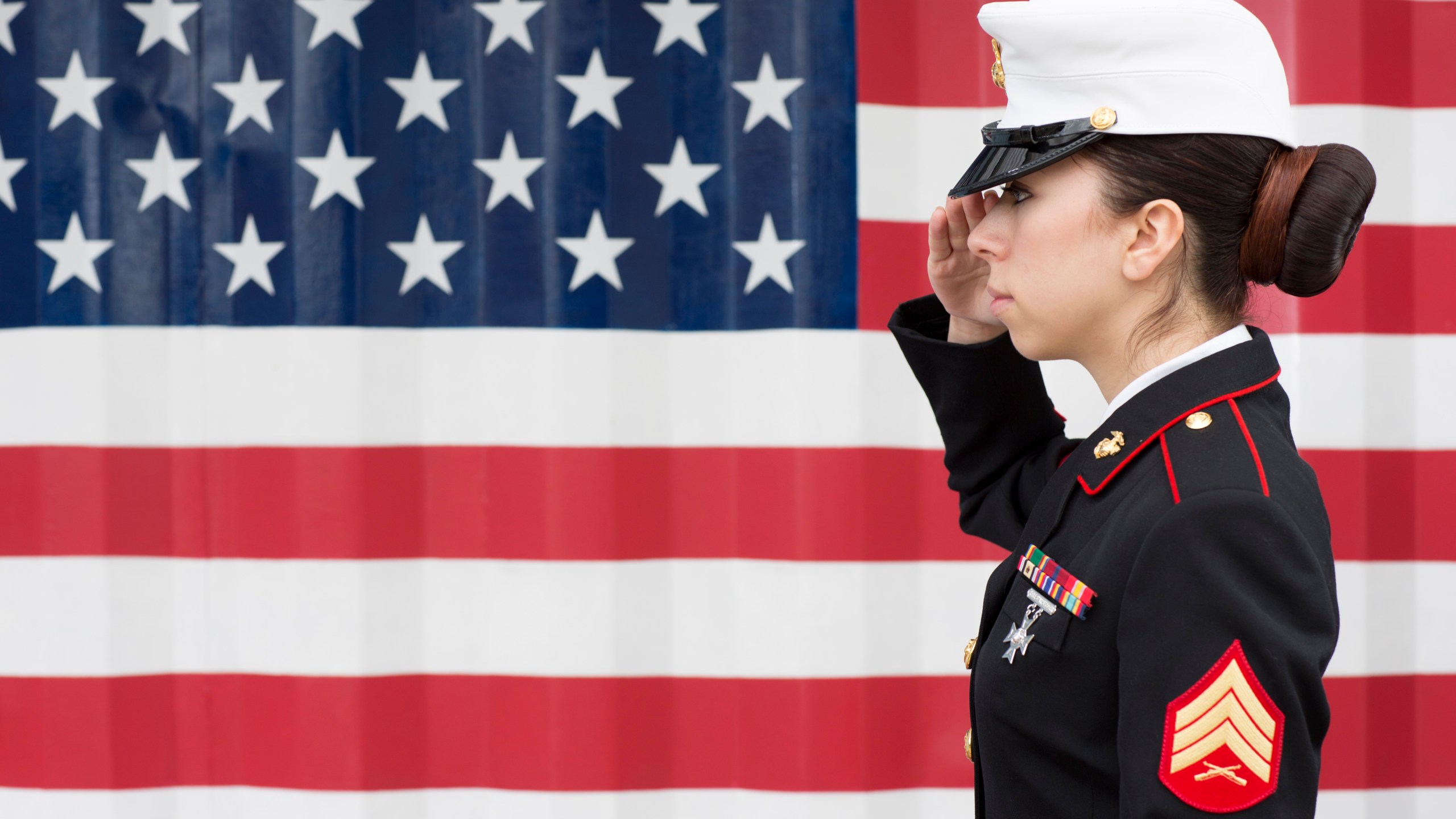 An American servicewoman in dress blues by US flag