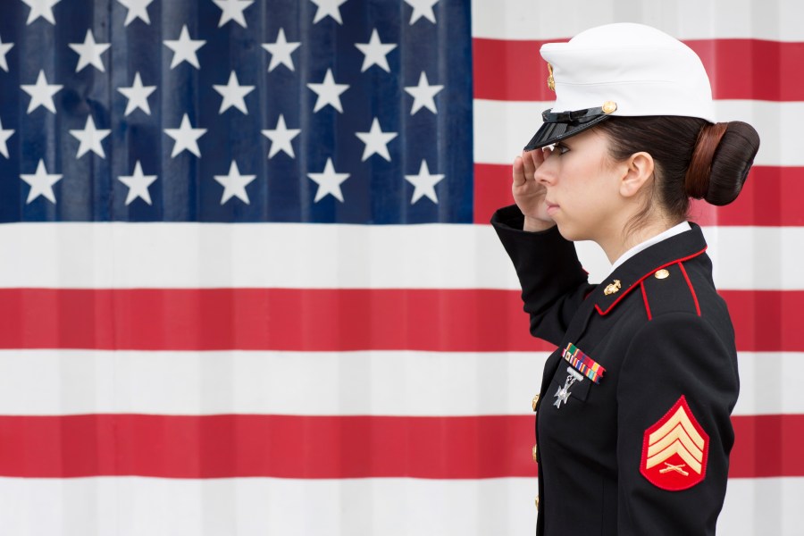 An American servicewoman in dress blues by US flag