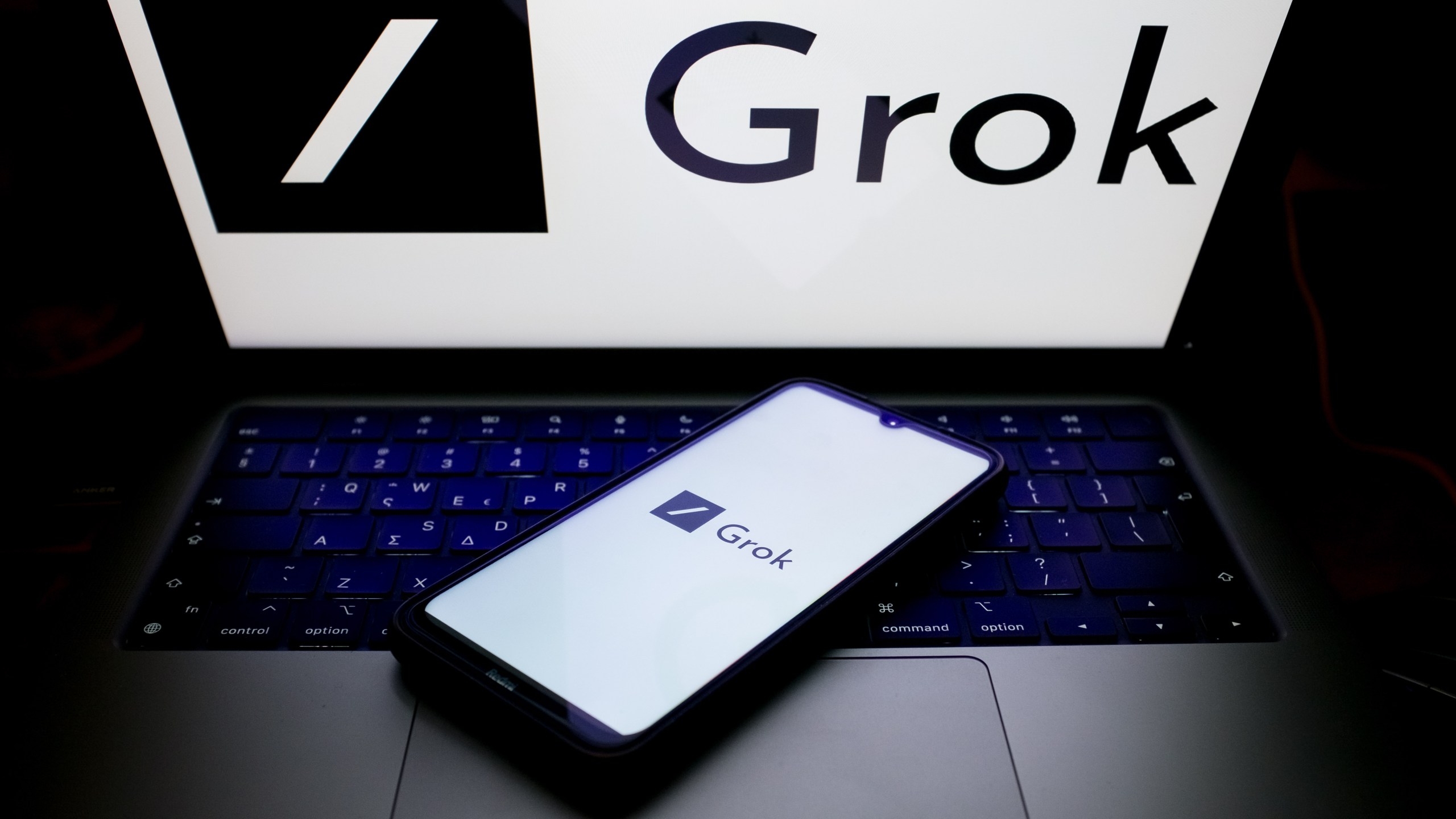 The Grok logo displayed on a smartphone screen and on a computer screen.