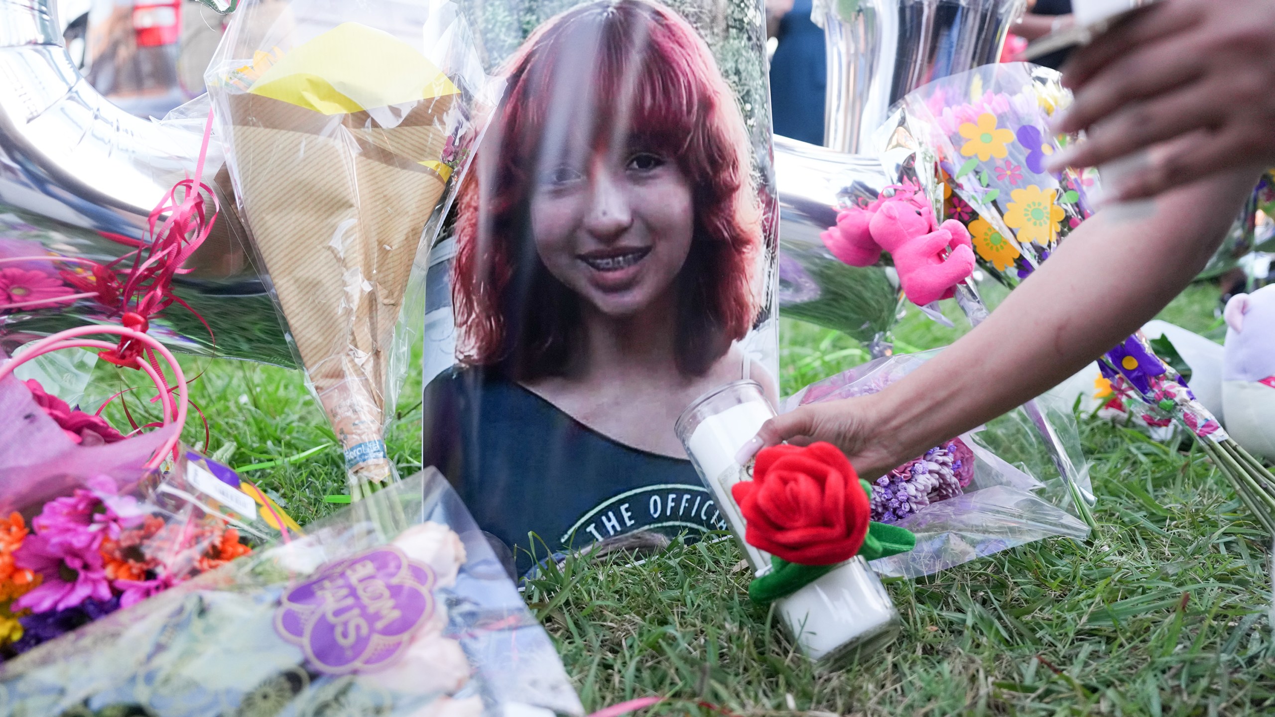 An attendee places a candle near a photo of 12-year-old Jocelyn Nungaray in Houston.