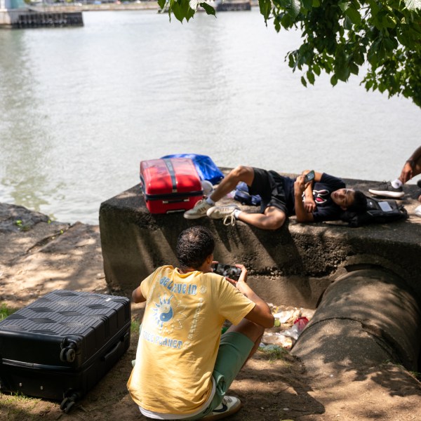 Young men from Venezuela, who are living in a tent, sit with their luggage after reaching their time limits at city-run shelters for migrants and their families on August 12, 2024, in New York City.