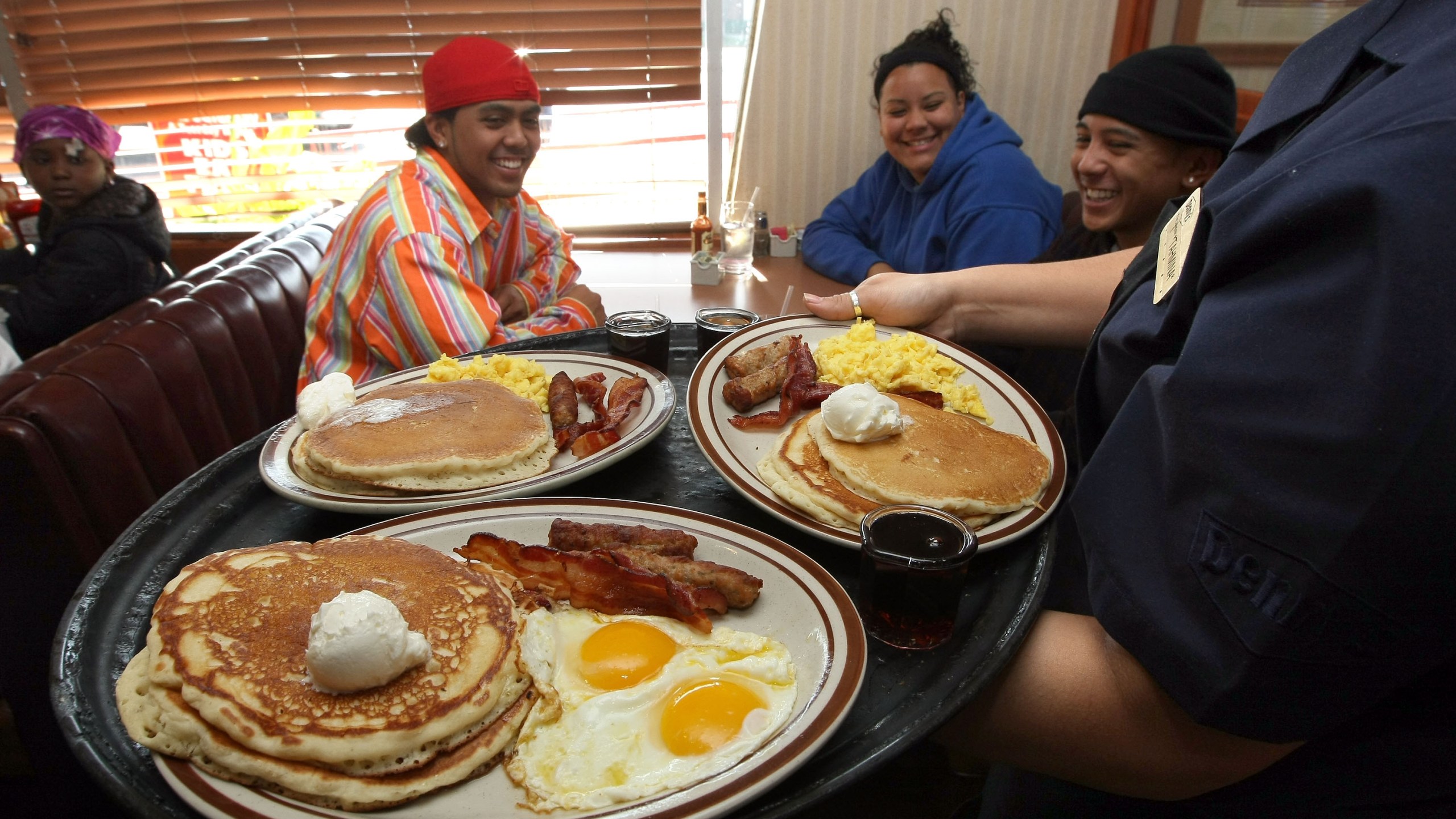 A waitress at Denny's delivers food to customers.