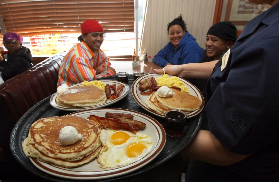 A waitress at Denny's delivers food to customers.