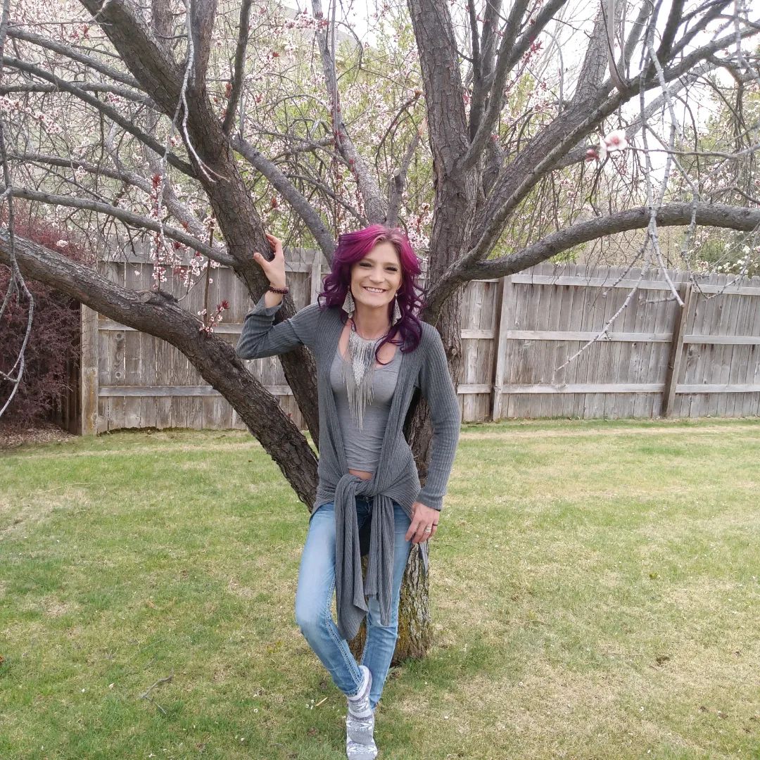 Kaysey Yoder in front of a tree with pink hair.