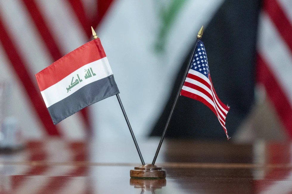 The flags of Iraq and the United States appear on a table.