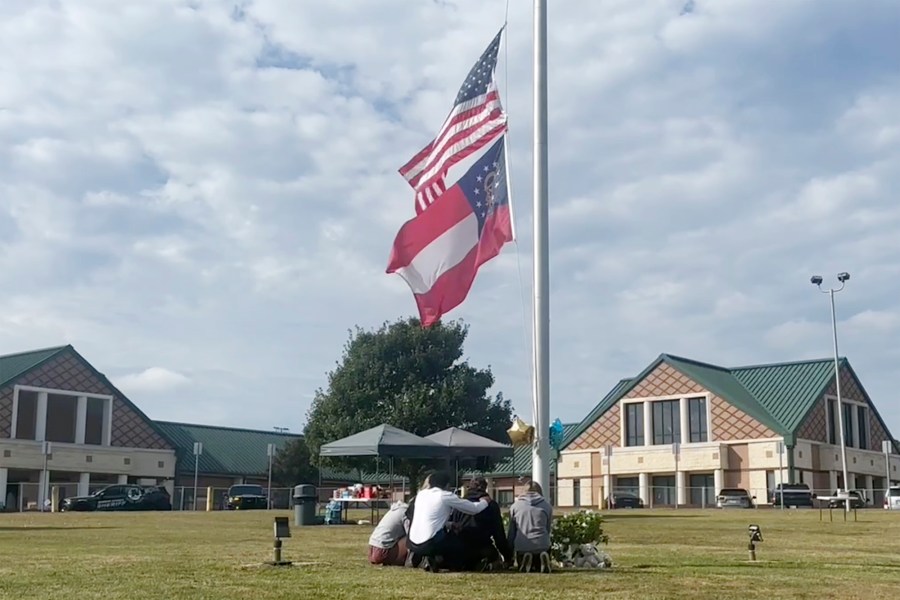 People gather at the flagpole outside the entrance to Apalachee High School on Thursday, Sept. 5, 2024 in Winder, Ga., a day after deadly shootings at the school. (AP Photo/Sharon Johnson)