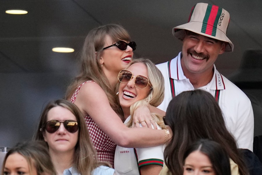 Taylor swift, left, hugs Brittany Mahomes as Travis Kelce looks on during the men's singles final between Jannik Sinner, of Italy, and Taylor Fritz, of the United States, at the U.S. Open tennis championships, Sunday, Sept. 8, 2024, in New York. (AP Photo/Kirsty Wigglesworth)