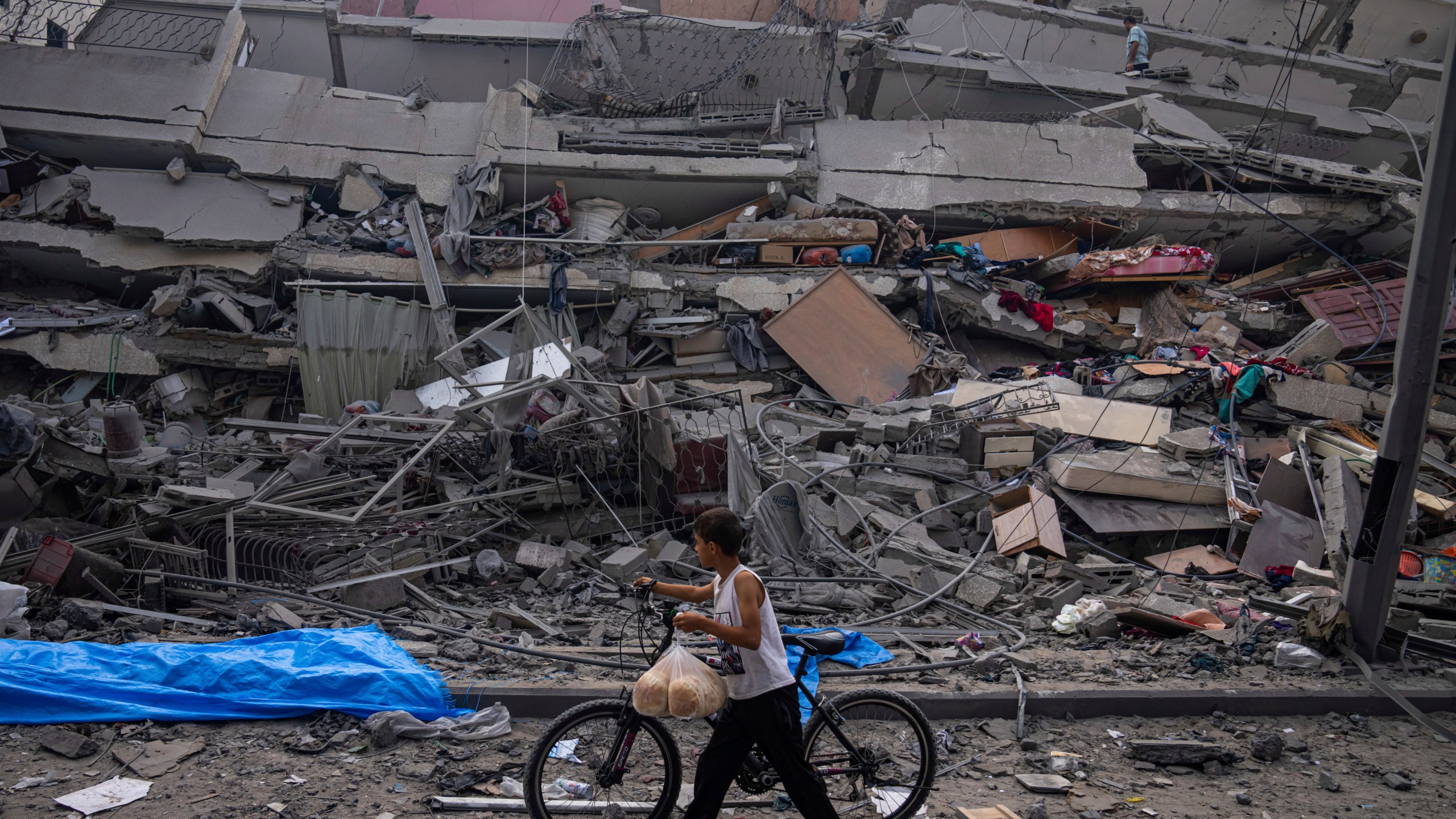 FILE - A Palestinian child walks with a bicycle by the rubble of a building after it was hit by an Israeli airstrike, in Gaza City, Oct. 8, 2023. (AP Photo/Fatima Shbair, File)