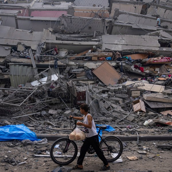 FILE - A Palestinian child walks with a bicycle by the rubble of a building after it was hit by an Israeli airstrike, in Gaza City, Oct. 8, 2023. (AP Photo/Fatima Shbair, File)