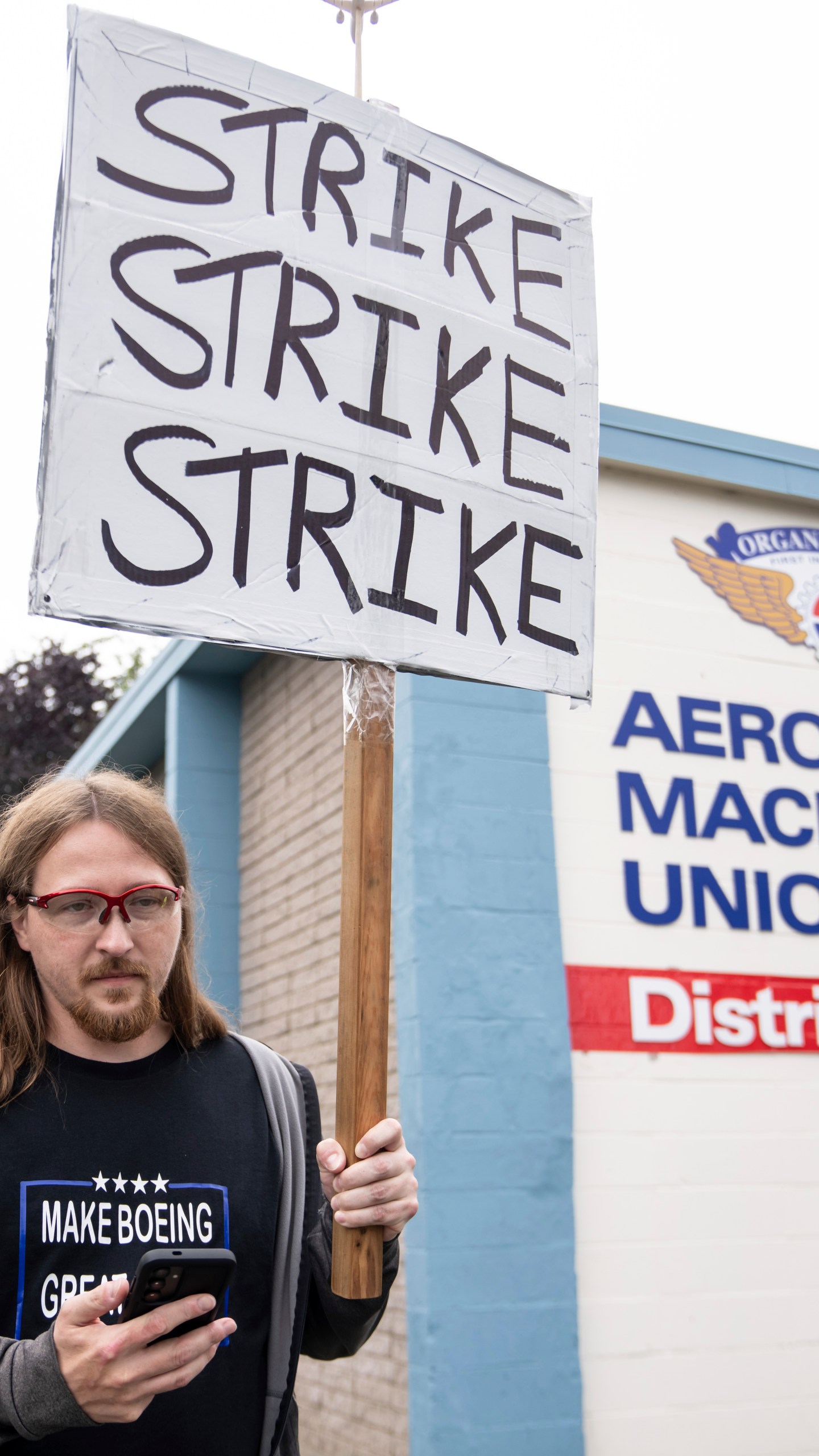 An International Aerospace Machinists union member holds a sign encouraging a strike.