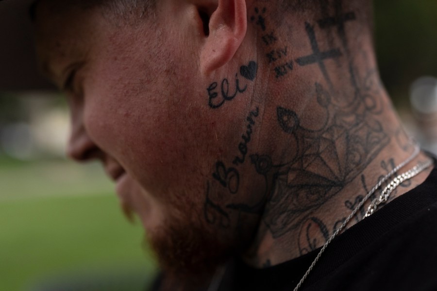 With his stepson's name tattooed below his ear, Tyler Brown, stepfather of Elijah Ott, who died of a fentanyl overdose at 15, looks at a park bench dedicated to Elijah in Paso Robles, Calif., Friday, Aug. 2, 2024. (AP Photo/Jae C. Hong)