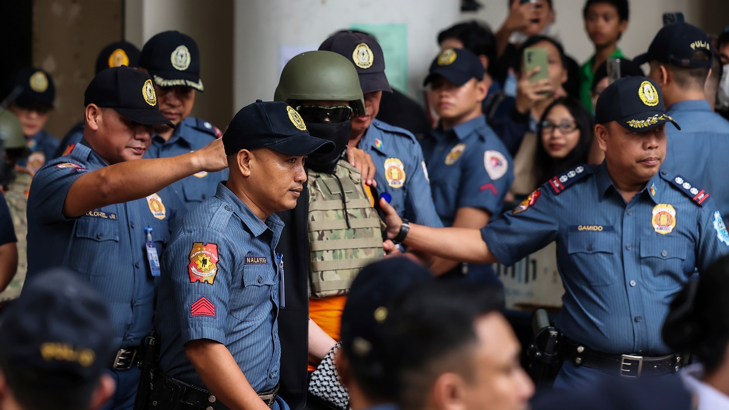 Apollo Carreon Quiboloy, center, wearing a helmet and flak jacket, a Filipino preacher charged with human trafficking, leaves the Pasig Regional Trial Court in Pasig City, Philippines, Friday, Sept. 13, 2024. (AP Photo/Gerard Carreon)