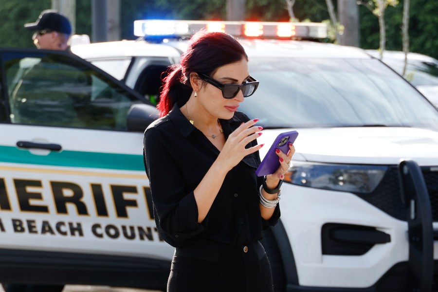 Laura Loomer uses her cell phone near Trump International Golf Club after police closed off the area following the apparent assassination attempt of Republican presidential nominee former President Donald Trump in West Palm Beach, Fla., Sunday, Sept. 15, 2024. (AP Photo/Terry Renna)