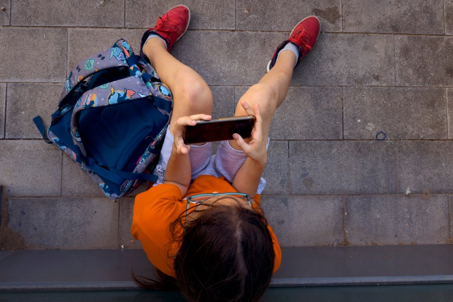 FILE - A 11-year-old boy plays with his father's phone outside school in Barcelona, Spain, Monday, June 17, 2024. (AP Photo/Emilio Morenatti, File)