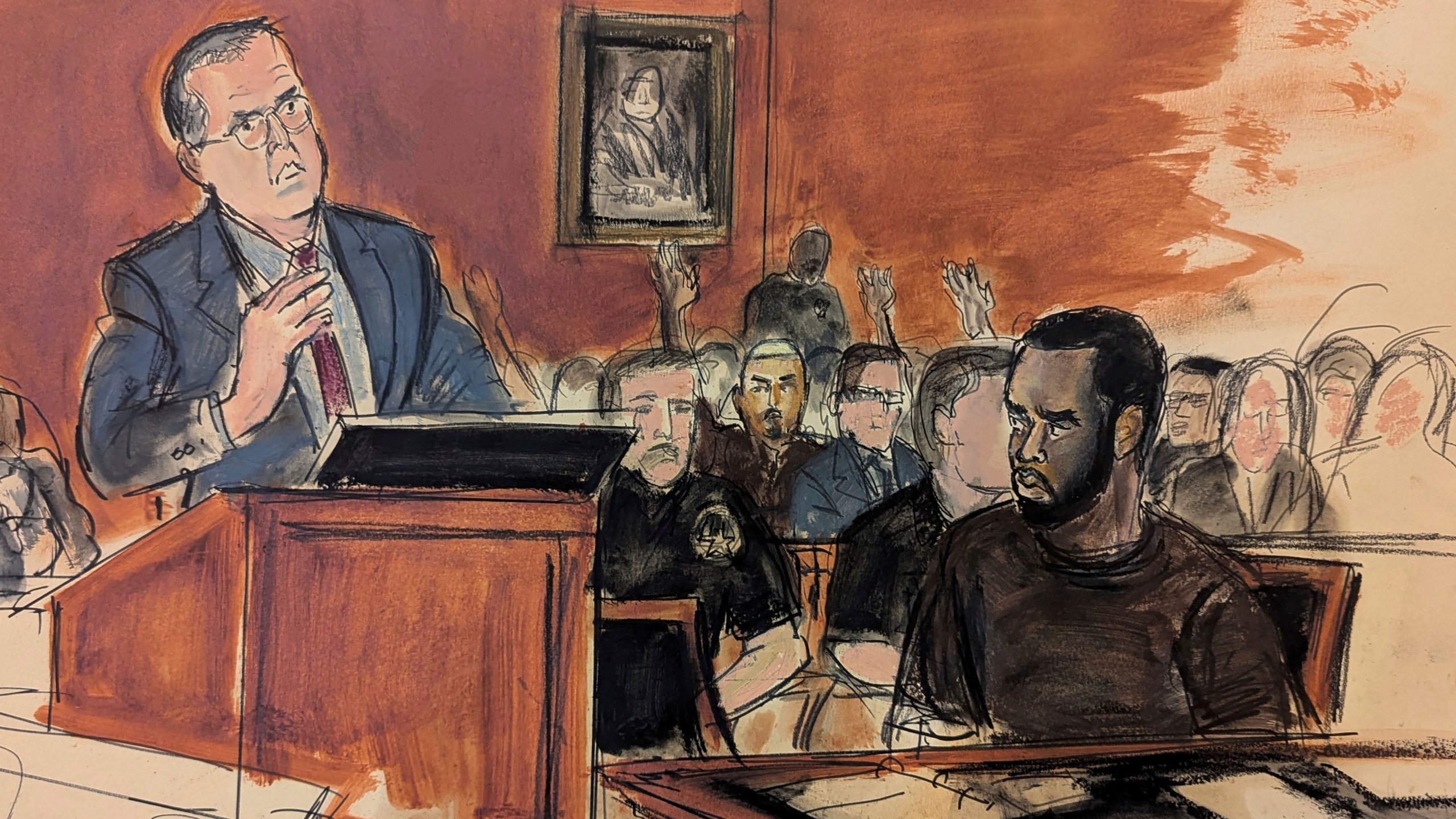 In this courtroom sketch, Sean Combs, seated right, looks at his attorney, Marc Agnifilo, left, as he delivers his bail argument as Combs' family in the gallery, background, raise their hands indicating to Judge Tarnofsky that they are in attendance, to bolster the defense attorney's bail argument, Tuesday, Sept. 17, 2024, in Manhattan Federal Court in New York. (Elizabeth Williams via AP)