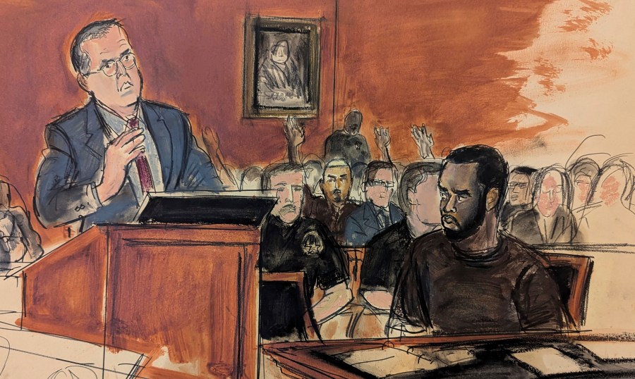 In this courtroom sketch, Sean Combs, seated right, looks at his attorney, Marc Agnifilo, left, as he delivers his bail argument as Combs' family in the gallery, background, raise their hands indicating to Judge Tarnofsky that they are in attendance, to bolster the defense attorney's bail argument, Tuesday, Sept. 17, 2024, in Manhattan Federal Court in New York. (Elizabeth Williams via AP)