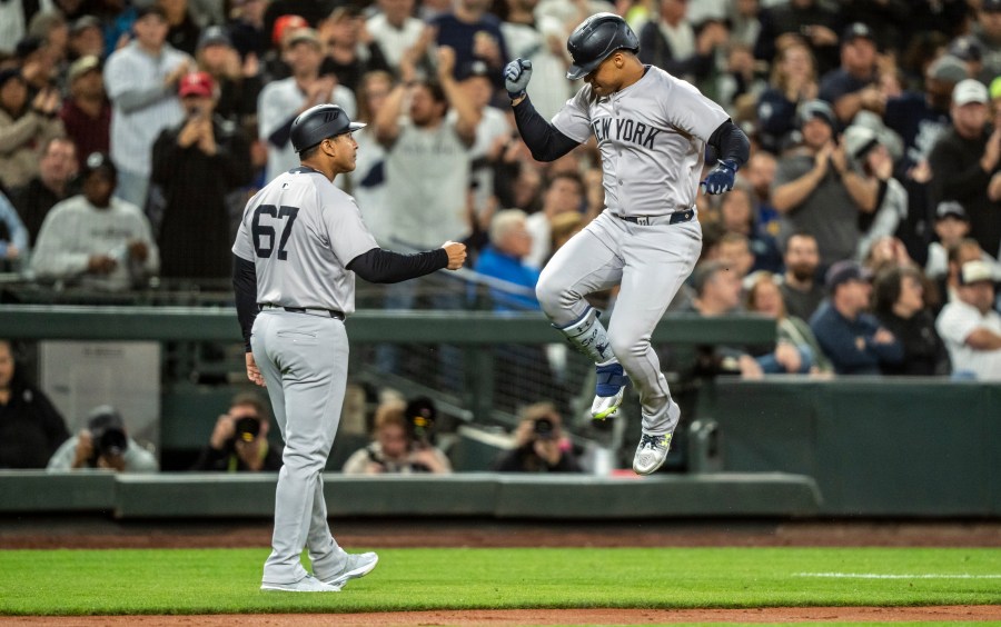 New York Yankees' Juan Soto, right, celebrates with third base coach Luis Rojas after hitting a two-run home run during the fourth inning of a baseball game against the Seattle Mariners, Tuesday, Sept. 17, 2024, in Seattle. (AP Photo/Stephen Brashear)