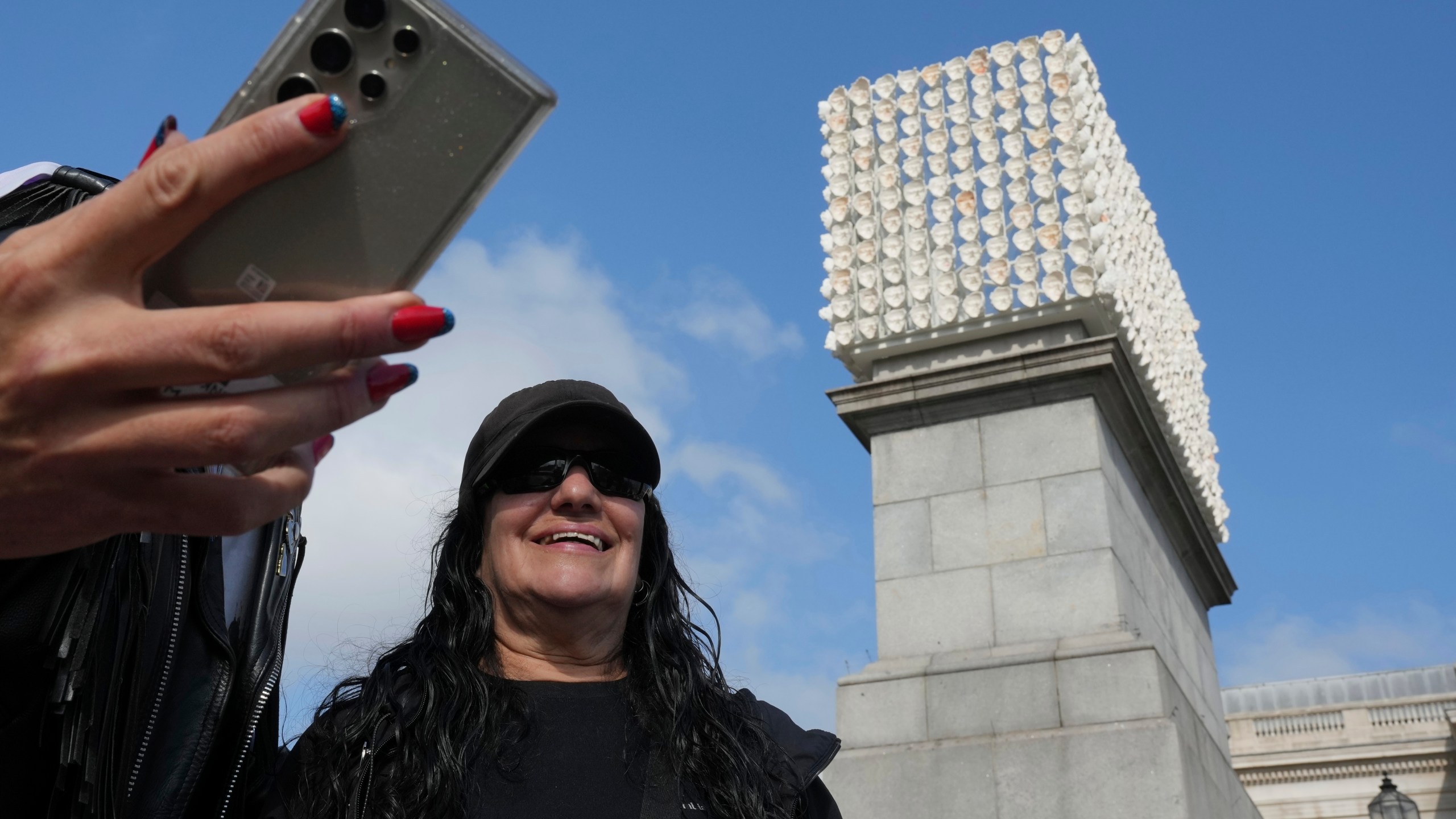 Mexican artist Teresa Margolles poses in front of her artwork "Mil Veces un Instante (A Thousand Times in an Instant)" for the Fourth Plinth, marking 25 years of the ground-breaking commissioning programme for public art at Trafalgar Square, in London, Wednesday, Sept. 18, 2024. (AP Photo/Kin Cheung)