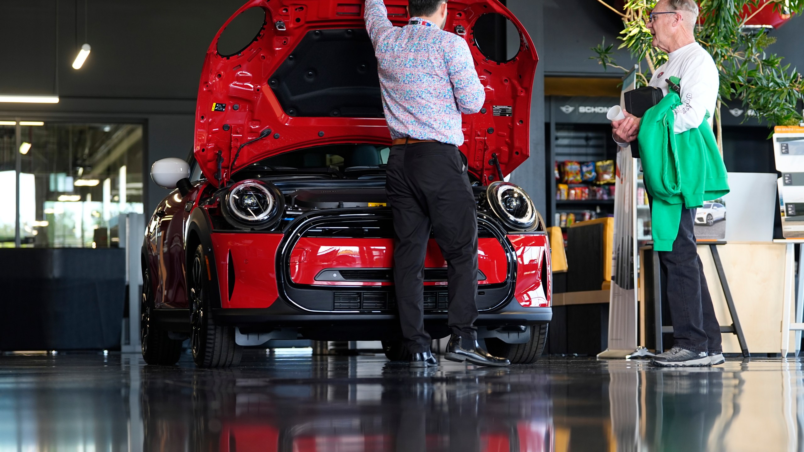 FILE - A salesperson shows an unsold 2024 Cooper SE electric hardtop to a prospective buyer in the showroom of a Mini dealership Wednesday, May 1, 2024, in Highlands Ranch, Colo. (AP Photo/David Zalubowski, File)