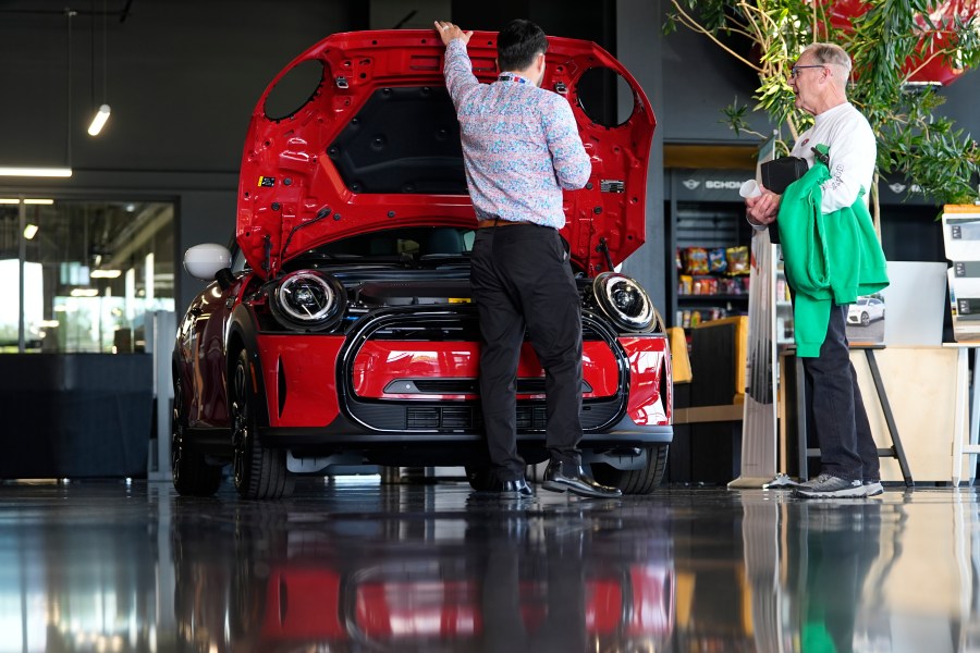 FILE - A salesperson shows an unsold 2024 Cooper SE electric hardtop to a prospective buyer in the showroom of a Mini dealership Wednesday, May 1, 2024, in Highlands Ranch, Colo. (AP Photo/David Zalubowski, File)